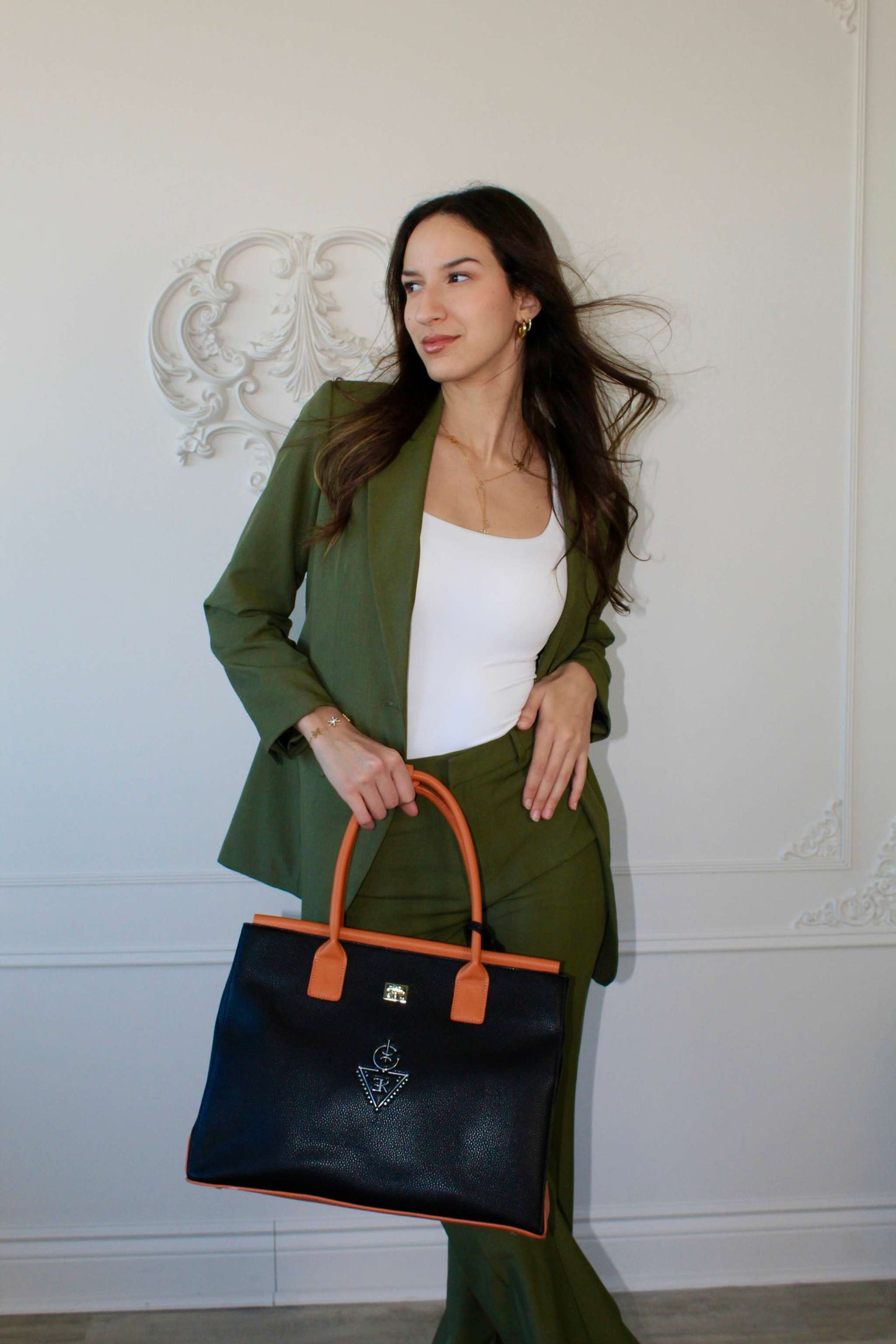 Femme élégante tenant un sac fourre-tout THILLELI noir avec ganses brunes, look moderne et chic.