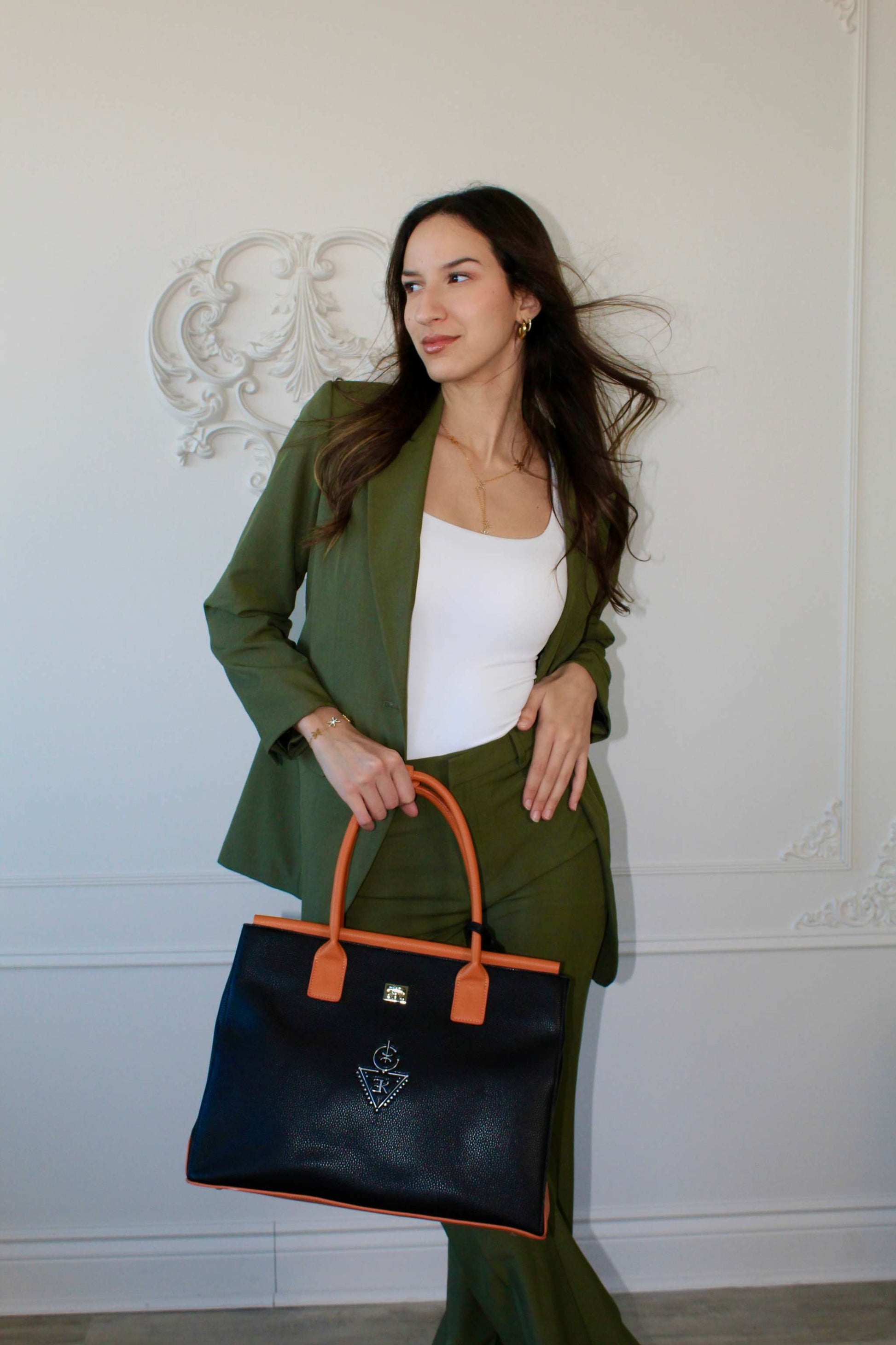 Femme élégante tenant un sac fourre-tout THILLELI noir avec ganses brunes, look moderne et chic.